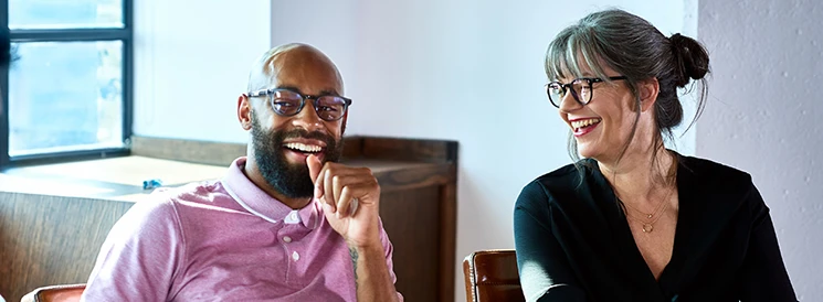 Man and woman smiling during meeting in board room